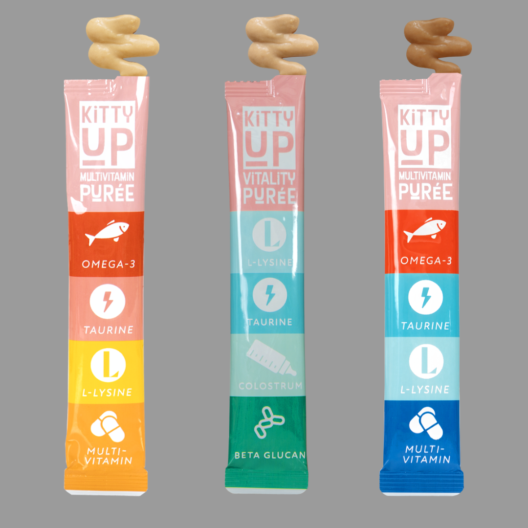 Three Kitty Up purée treat tubes—Multivitamin and Vitality—with swirls of purée on top, shown on a gray background.